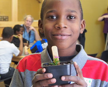 boy with school plant project, photo by Vienna Volante