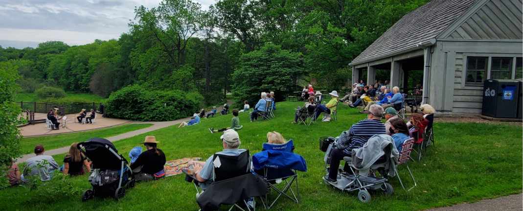 People seated on the hill for music in the gardens