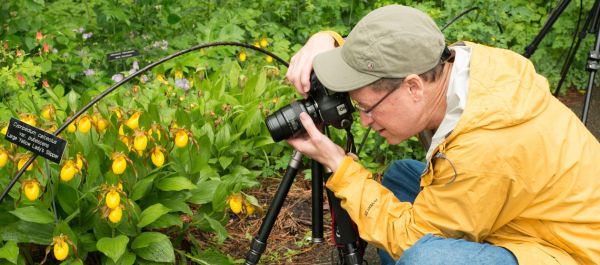 Man in a yellow raincoat photographing lady slippers