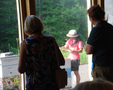 Visitors watch beekeeper Ping as she opens and inspects a hive.
