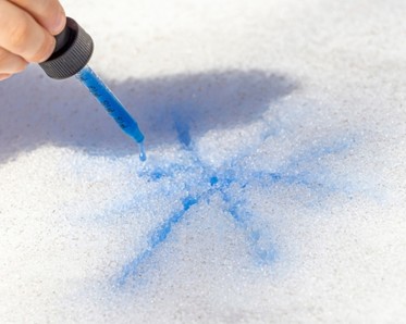 child using dropper to make colored snowflake 