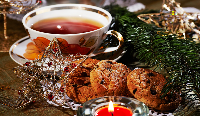Red tea with cookies, star ornament & candle on a table 