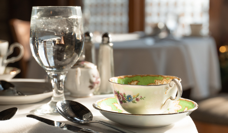 Porcelain tea cup and glass of water on a white tablecloth