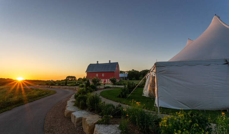 Red barn with white tent at sunset