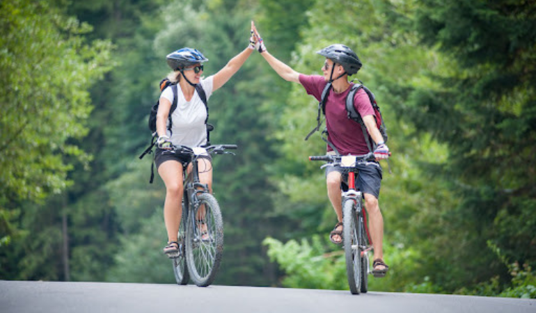 Man and woman on bikes high-fiving
